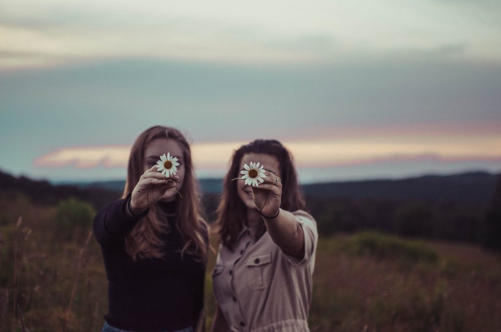deux amis tenant une fleur à la main