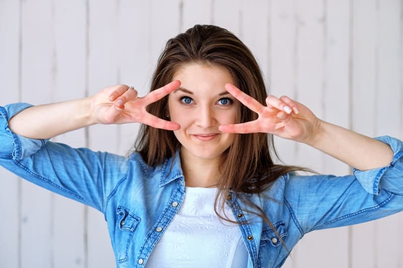 la fille écarte ses doigts devant sa tête