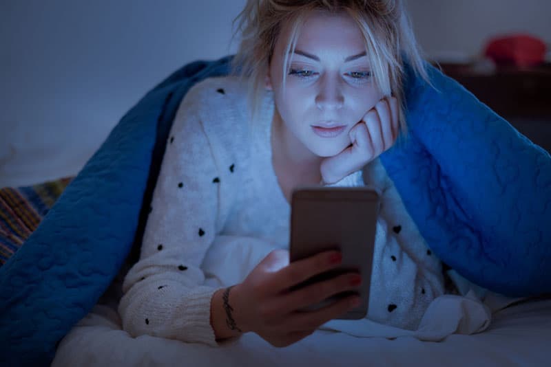 triste femme blonde au téléphone dans son lit