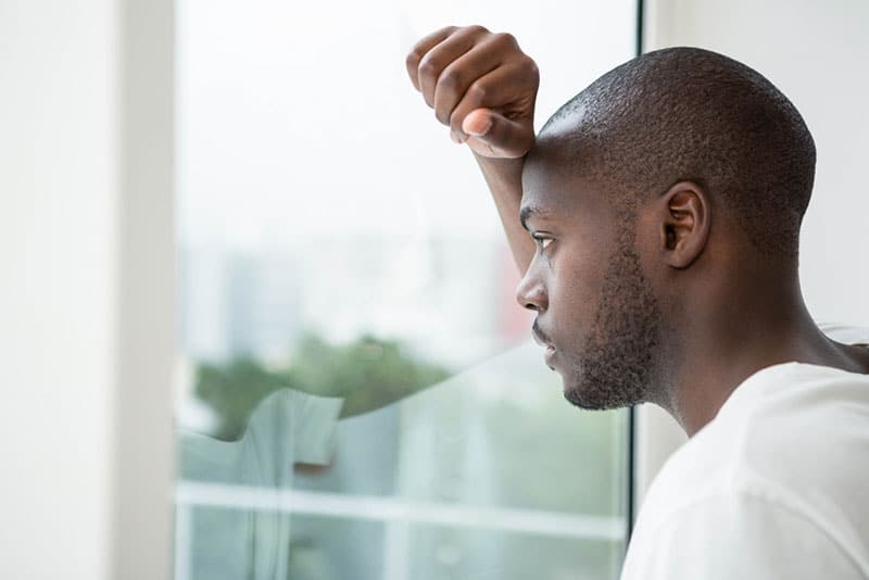 triste jeune homme noir près de la fenêtre