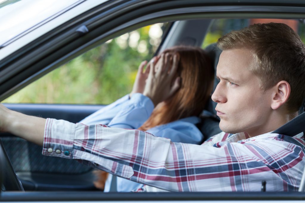 un homme conduit une voiture pendant qu'une femme tient sa tête