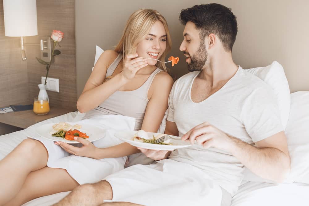 un homme et une femme mangent au lit