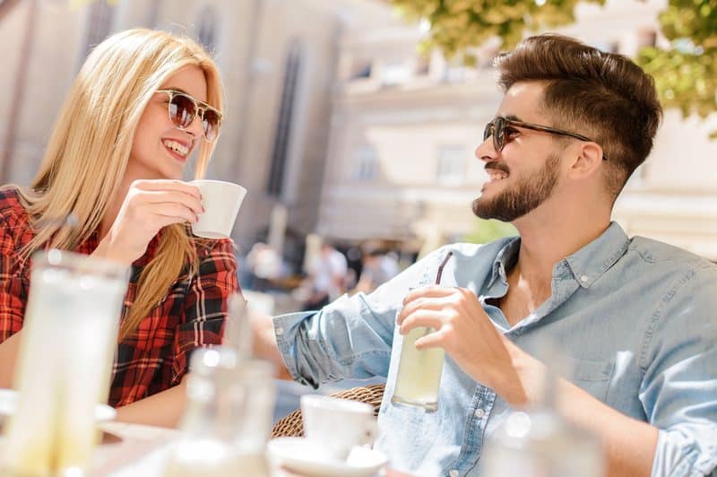 un homme et une femme sont assis à boire du café et à se regarder