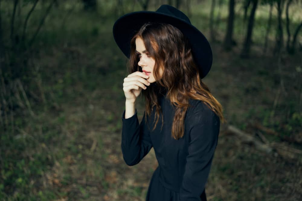 une femme avec un chapeau sur la tête se tient dans les bois