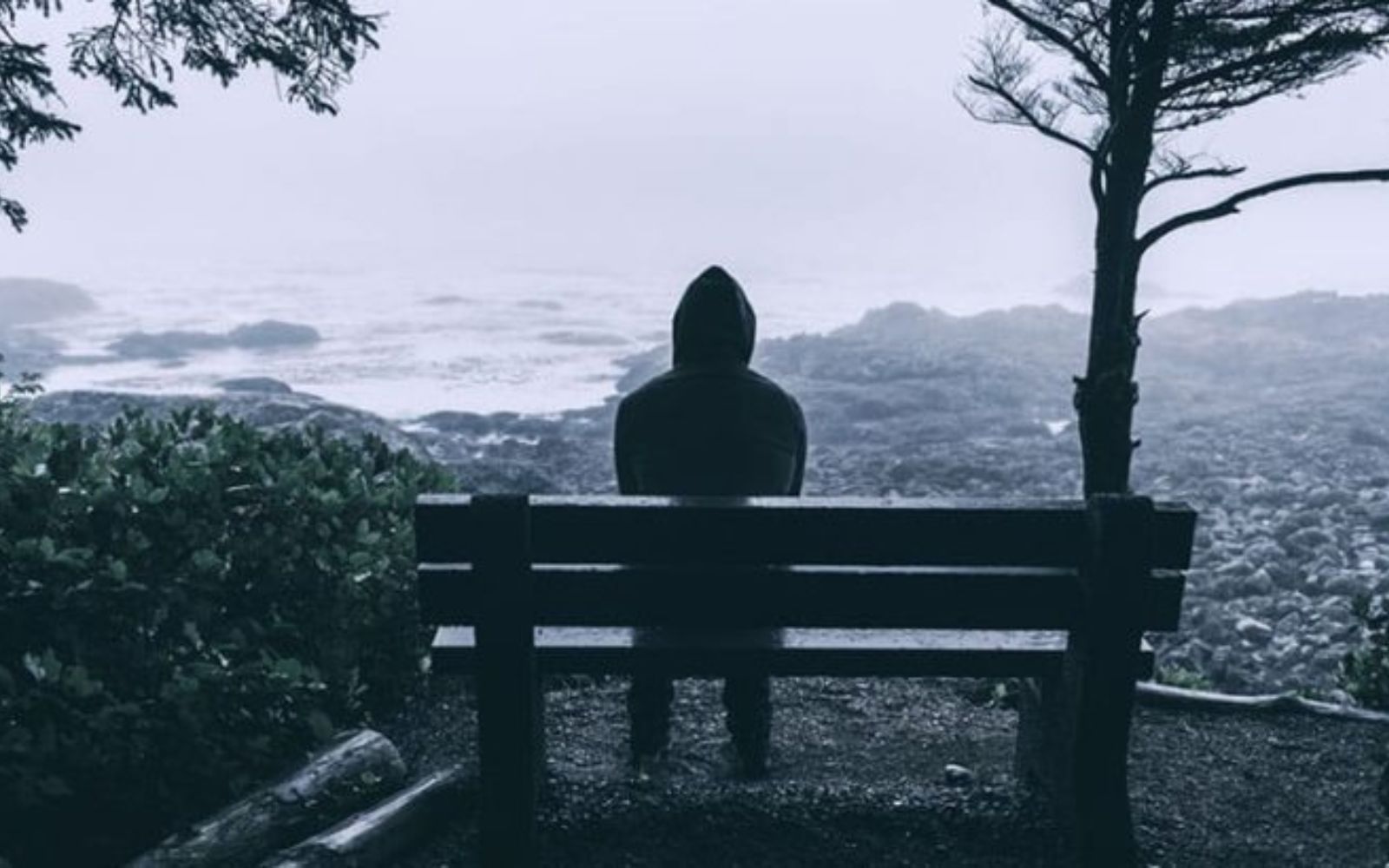 triste jeune homme a capuche assis sur un banc