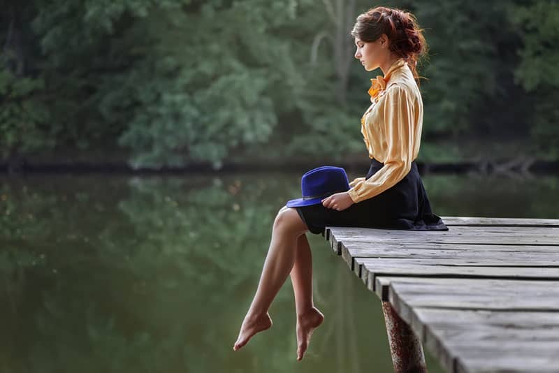 jeune femme assise sur le quai près de l'eau
