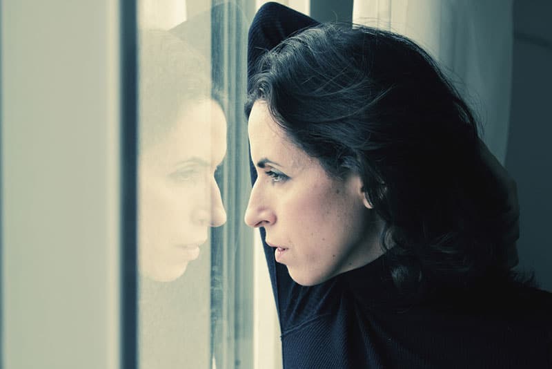 triste brune mature regardant par la fenêtre