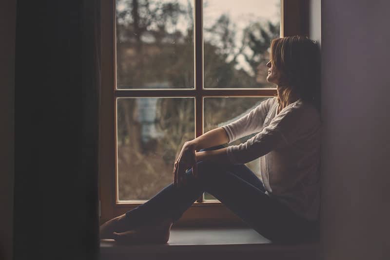 triste jeune femme assise près de la fenêtre