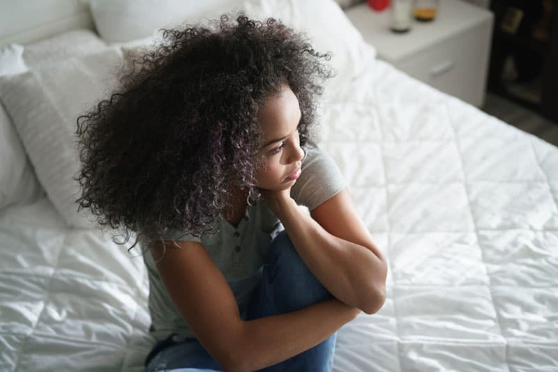 triste jeune femme noire assise sur le lit
