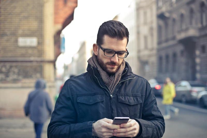 un homme avec un téléphone à la main marche dans la rue