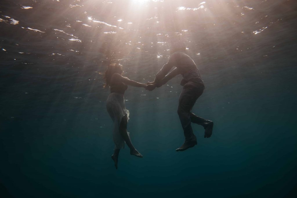 un homme et une femme se tenant la main alors qu'ils nagent dans l'eau