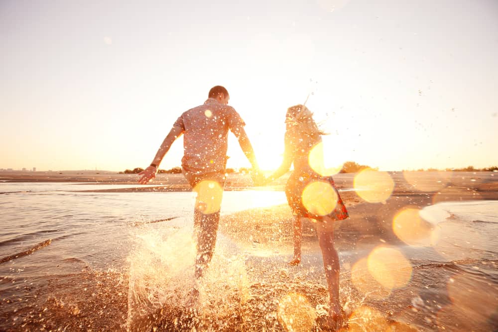 un homme et une femme traversent la plage