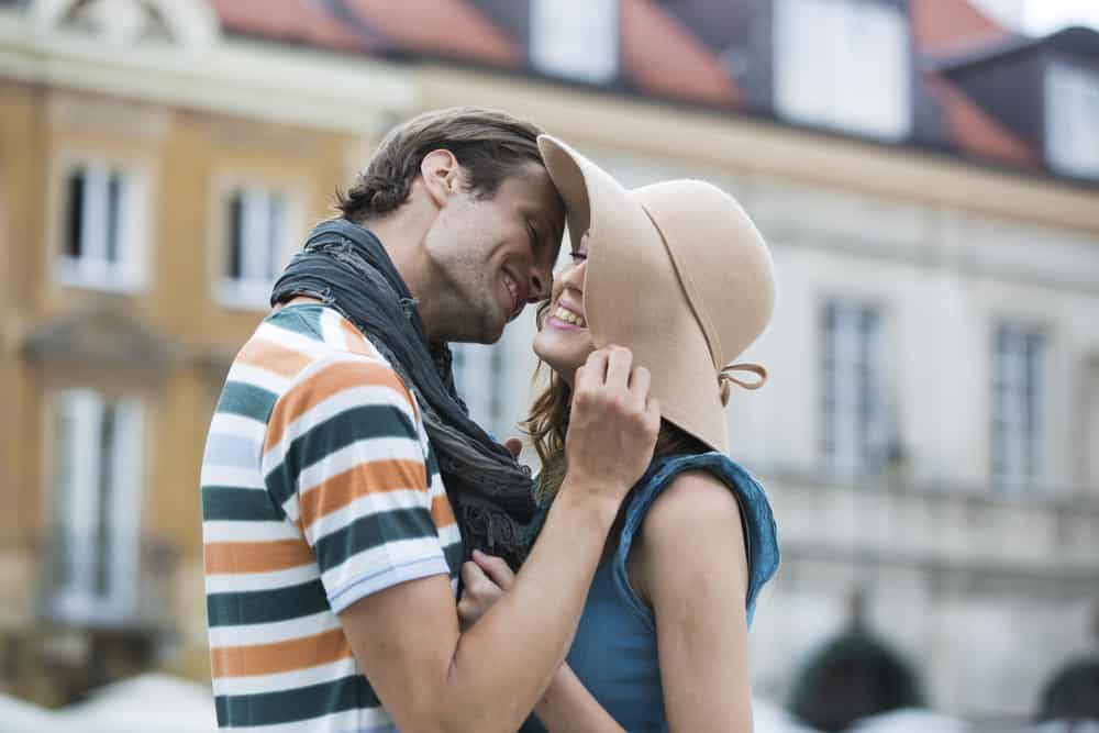 un homme veut embrasser une femme avec un chapeau