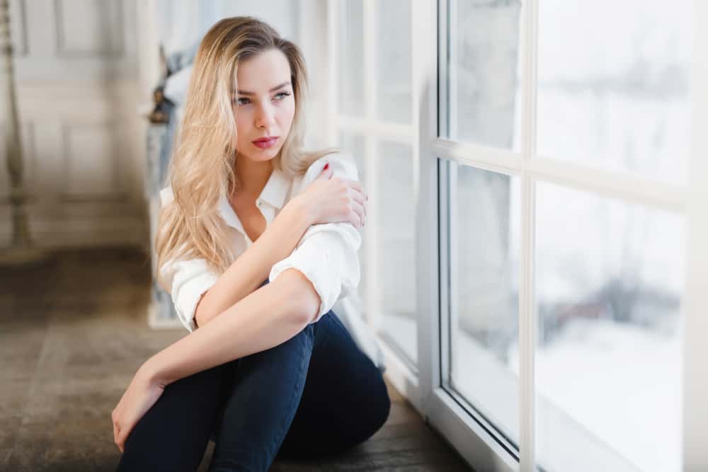 une femme blonde imaginaire assise près de la fenêtre