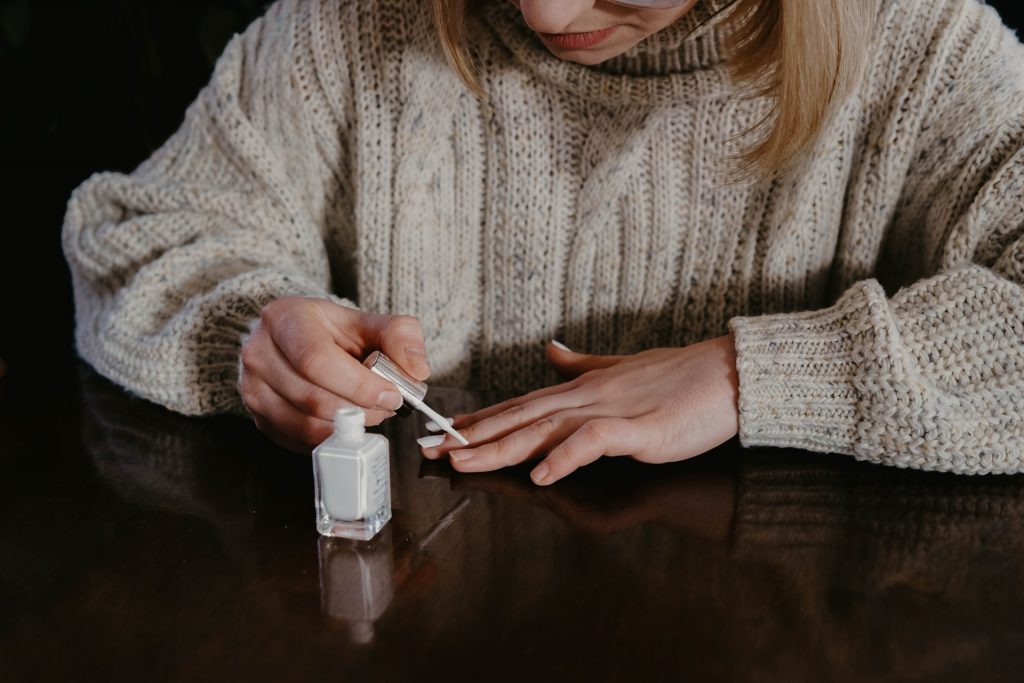 une femme se peint les ongles