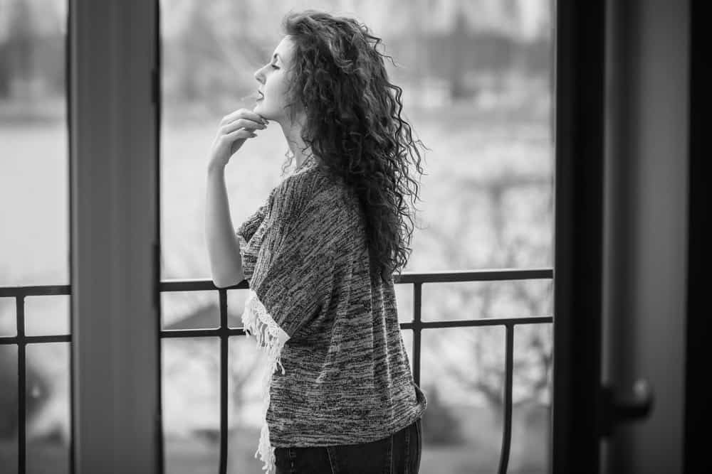 une femme triste se tient sur le balcon