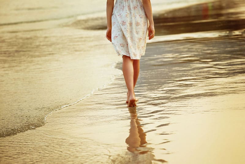 jeune femme en robe marchant sur la plage