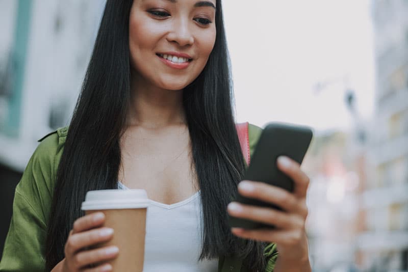 jeune femme, à, café, dans, une, main, et, téléphone, dans, autre