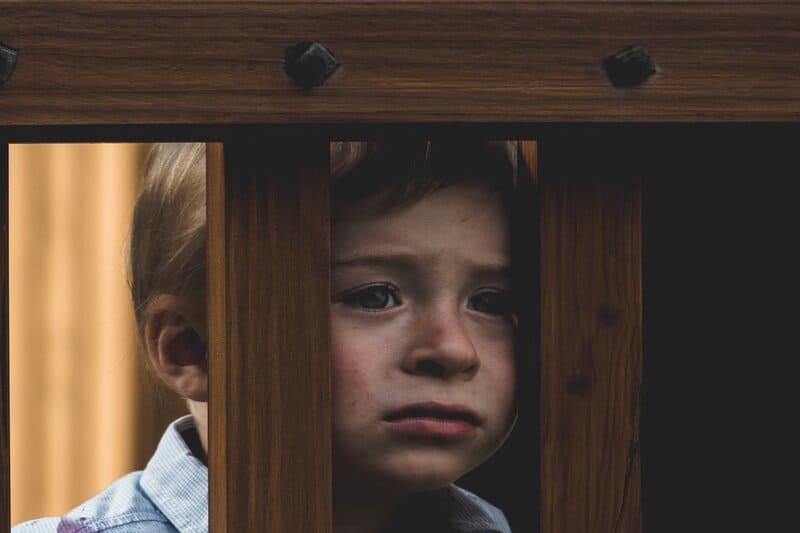 l'enfant regarde tristement à travers les barreaux