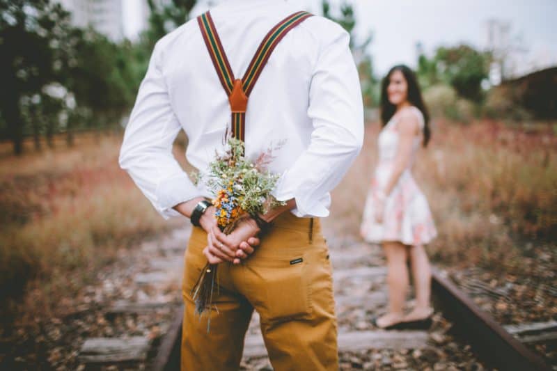 l'homme tient des fleurs derrière son dos