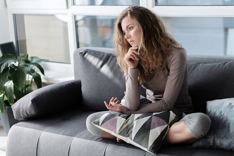 triste jeune femme assise sur le canapé