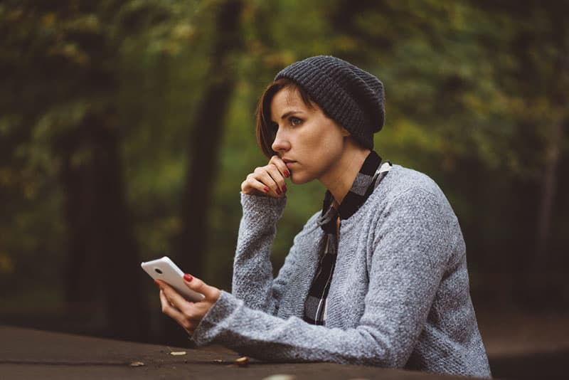 triste jeune femme avec un téléphone à l'extérieur