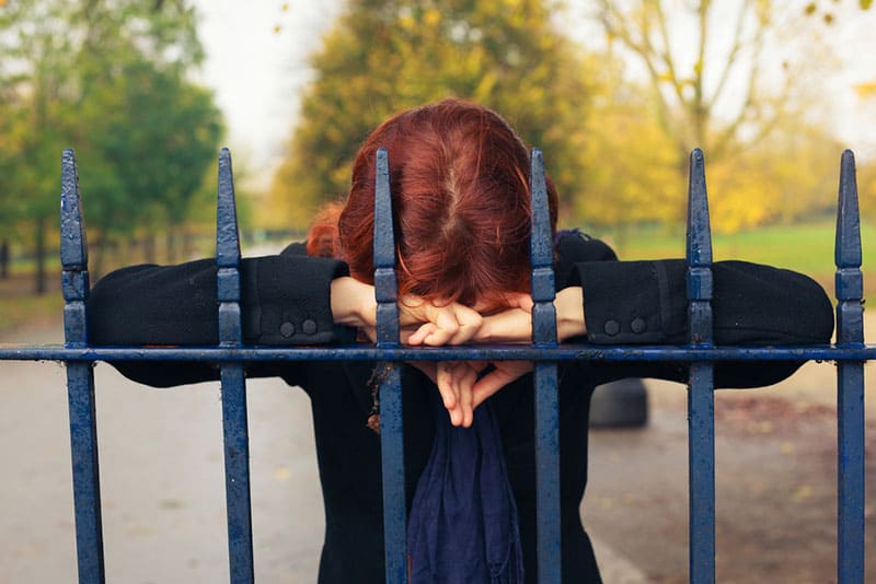 triste jeune femme rousse par la clôture