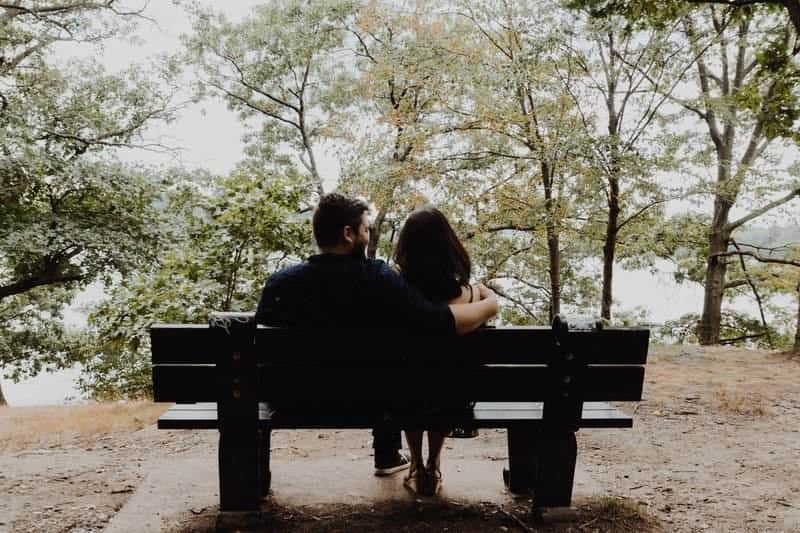 un homme et une femme assis sur un banc embrassant