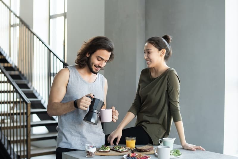 un homme et une femme dans la cuisine parler et boire du café
