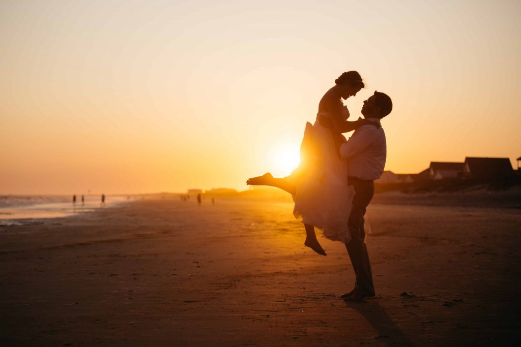 un homme porte une fille à la plage