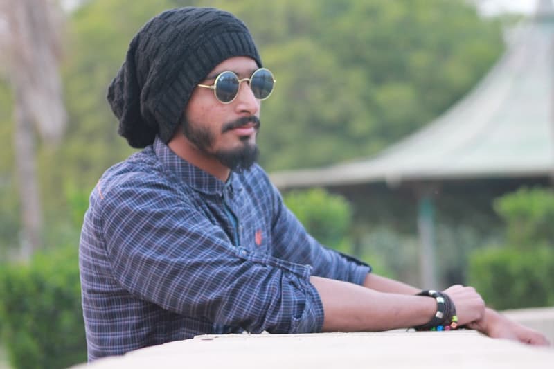 un homme sérieux avec un chapeau et un bracelet