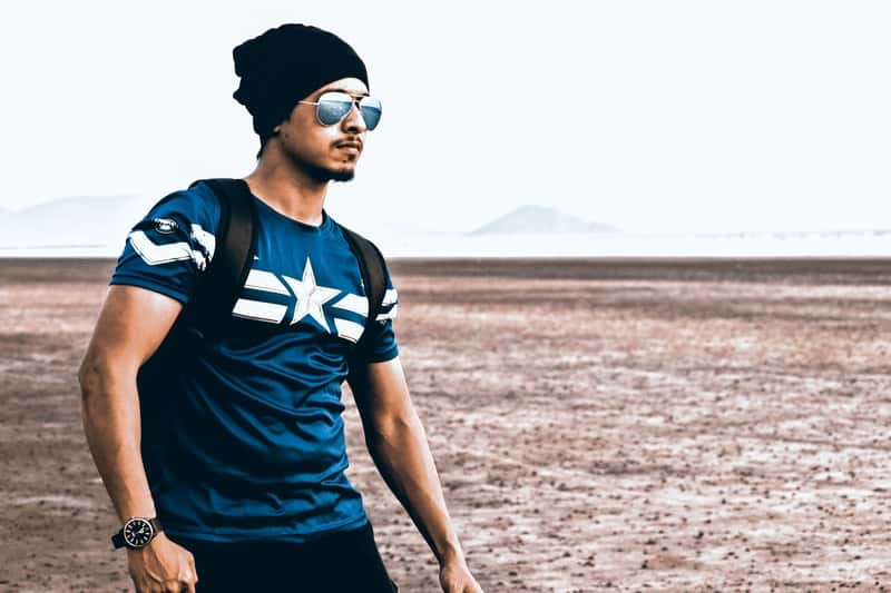 un homme sérieux avec un sac à dos traverse le désert