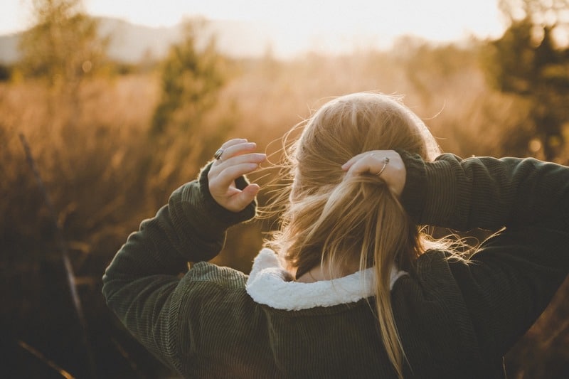 une femme se lie les cheveux dans la nature