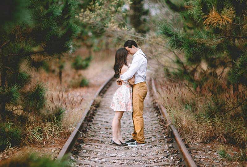 un homme et une femme embrassant par la voie ferrée