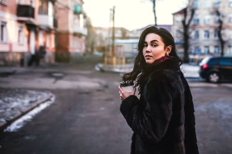 jeune brune avec du café dans la rue