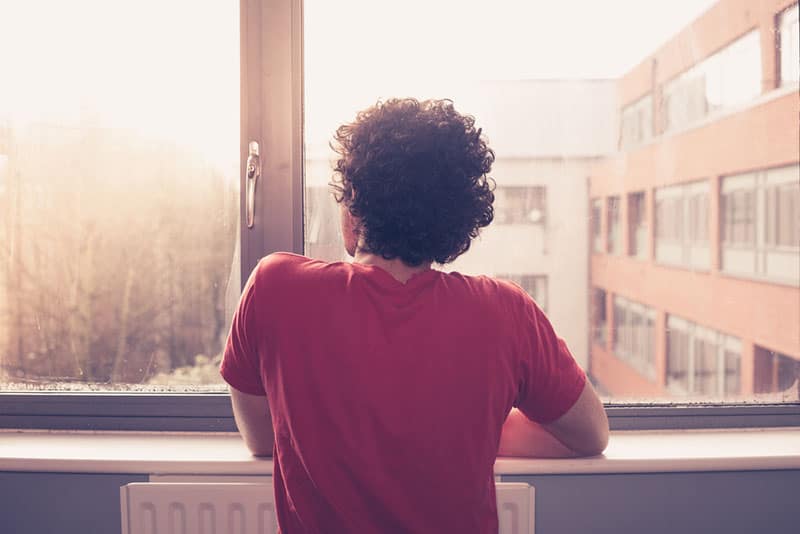 jeune homme aux cheveux bouclés par la fenêtre