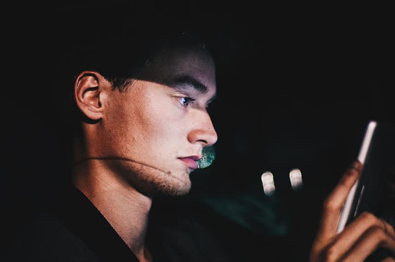 jeune homme textos dans l'obscurité