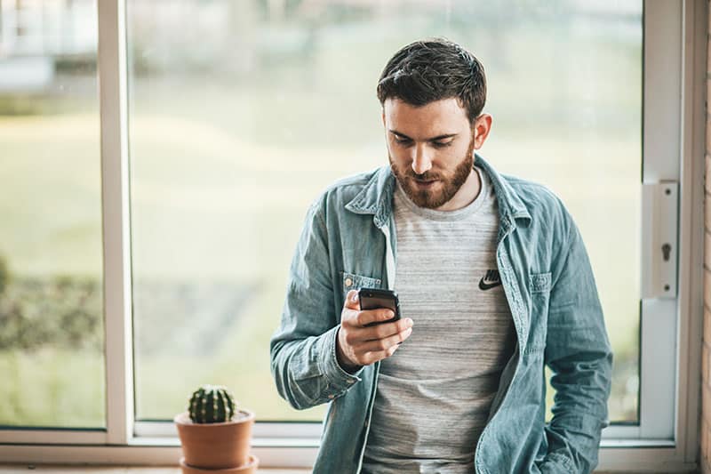 jeune homme textos par la fenêtre