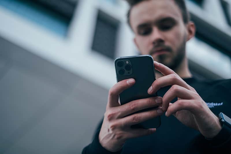 jeune homme textos sur téléphone