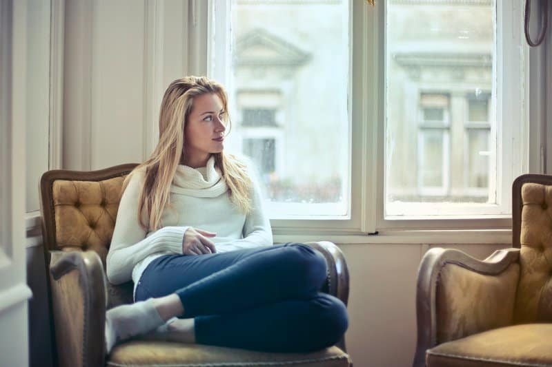 la femme blonde s'assied sur le canapé et pense