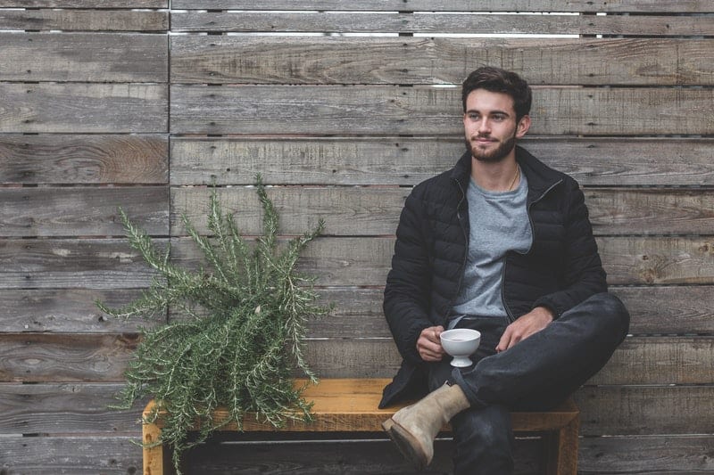 l'homme s'assoit et boit du café en détournant les yeux