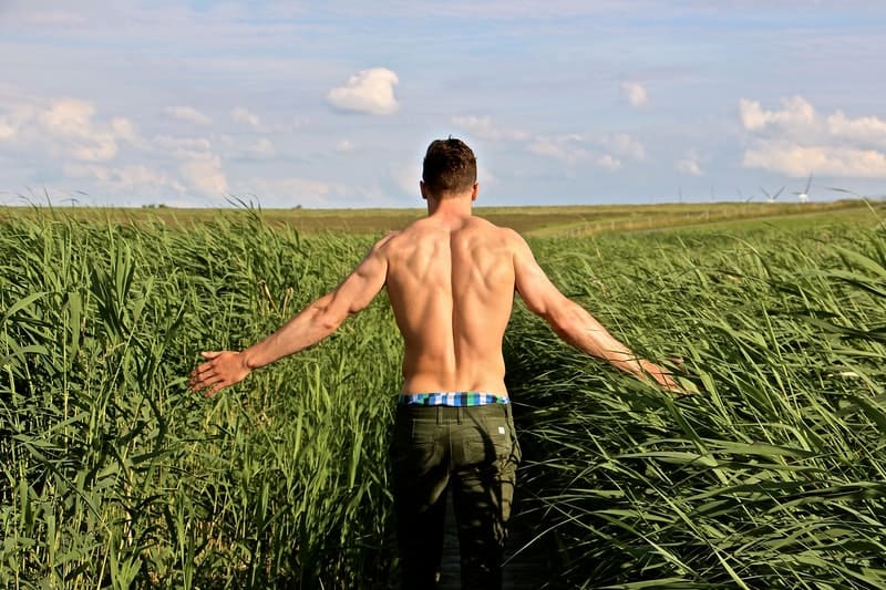 un homme à moitié nu marchant dans un champ
