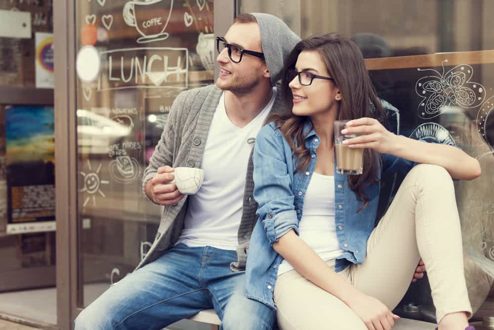 un homme et une femme s'assoient dans une vitrine et boivent du café