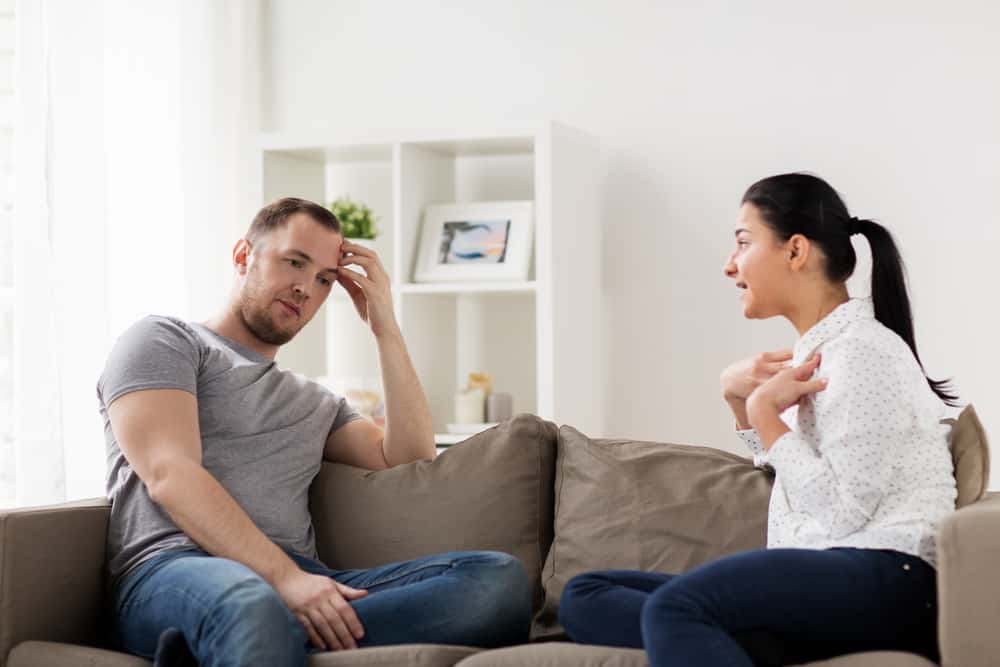 un homme et une femme s'assoient sur le canapé et se disputent