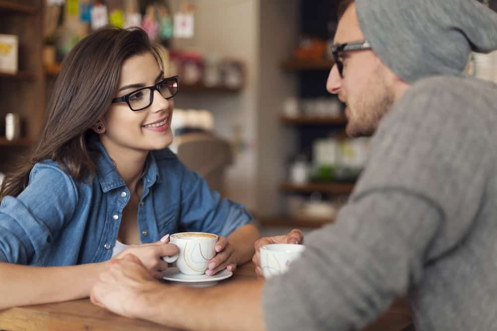 un homme et une femme sont assis à une table en buvant du café et en parlant
