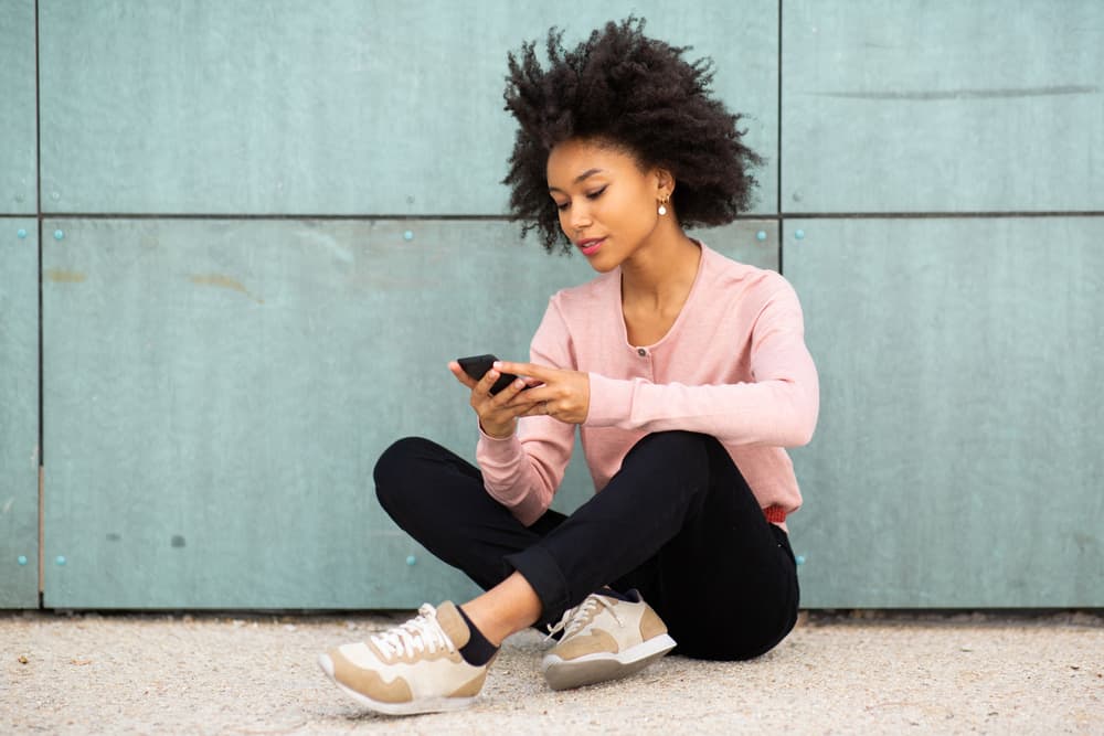 une femme assise avec un téléphone à la main