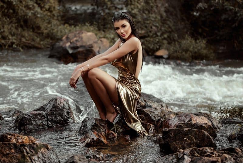 une femme assise sur une pierre, une rivière