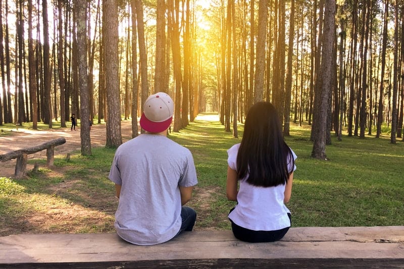 une femme et un homme assis sur un banc dans les bois