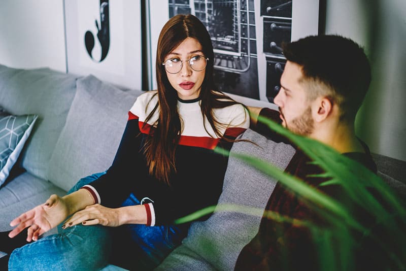 jeune couple ayant une conversation sérieuse sur canapé