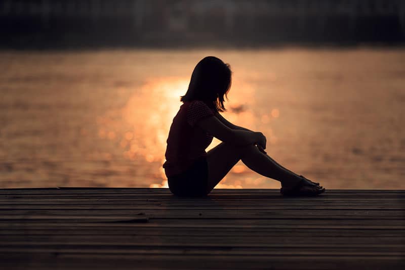 silhouette d'une jeune femme triste au bord de l'eau